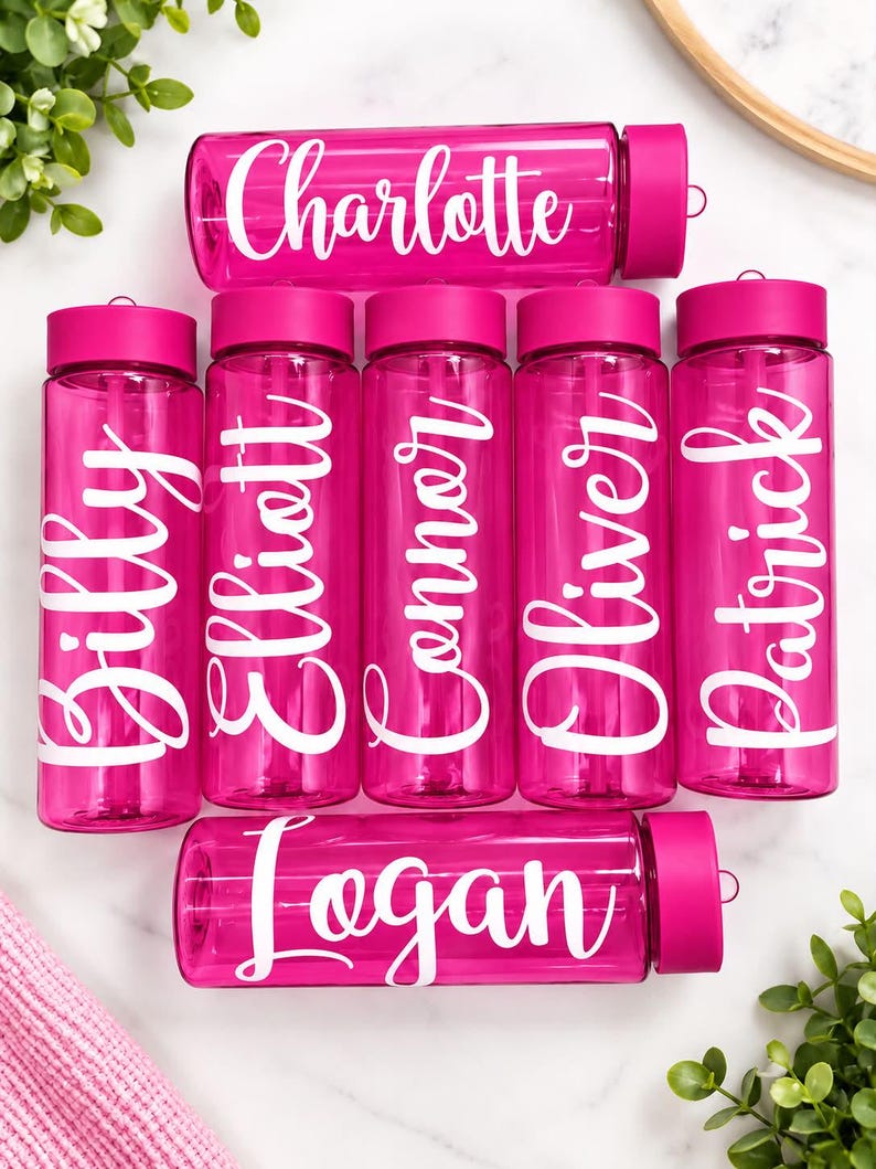 May include: Seven translucent hot pink plastic water bottles with matching screw-top lids. Each bottle features a unique white script name printed on the side, including the names Charlotte, Billy, Elliott, Connor, Oliver, Patrick, and Logan.