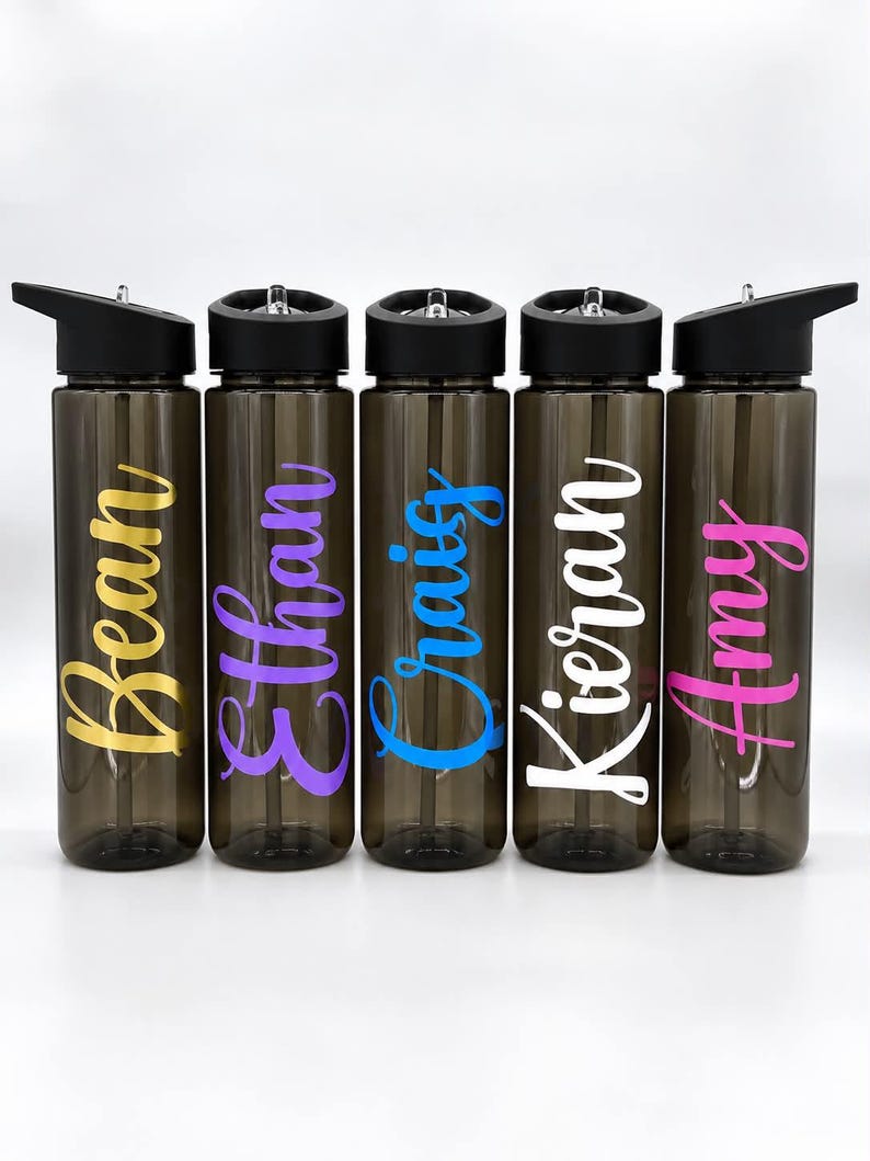 Pu&ograve; includere: Cinque borracce in plastica grigio scuro traslucido con tappi e cannucce neri. Ogni bottiglia presenta un nome in un carattere corsivo di colore diverso: Bean in giallo, Ethan in viola, Craig in blu, Kieran in bianco e Amy in rosa.