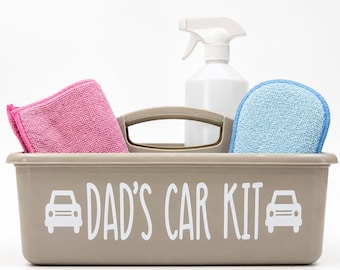 May include: A beige plastic storage caddy with a central handle, featuring the white text DAD'S CAR KIT flanked by two car icons. Inside the caddy are a white spray bottle, a folded pink microfiber cloth, and a blue textured cleaning sponge.