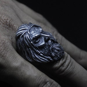 Puede incluir: Un anillo de plata con una escultura detallada de la cara de un hombre con una larga barba. El anillo se lleva en el dedo de una persona.