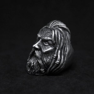 Puede incluir: Un anillo de plata con una escultura detallada de la cara de un hombre con el pelo largo y barba.
