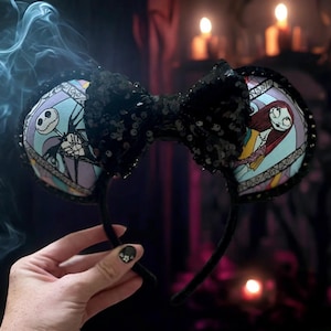 May include: Black sequin Minnie Mouse ears with a Nightmare Before Christmas design. One ear features Jack Skellington and the other features Sally.