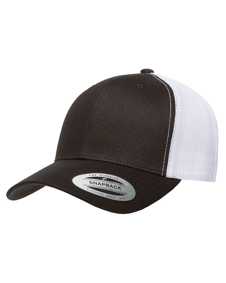 Puede incluir: Una gorra de b&eacute;isbol negra y blanca con una parte trasera de malla. La gorra tiene un panel frontal negro y un panel trasero de malla blanca. La gorra tiene una pegatina en la parte delantera que dice "The Classics Yupoong Snapback Since 1974".
