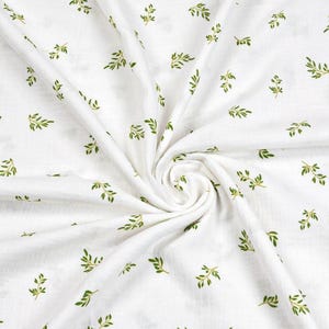 May include: White fabric with a repeating pattern of small green leaves. The leaves are detailed with visible veins and are scattered across the fabric. The fabric is gathered in a swirl, creating shadows and texture.
