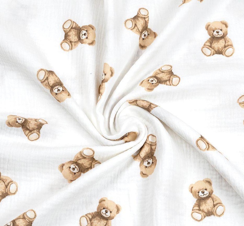 May include: White fabric with a repeating pattern of brown teddy bears. The bears are in various poses, some upright and others lying down. The fabric has a soft, textured appearance.