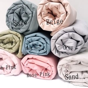 May include: Rolled up fabric swatches in various colours, including sage, beige, forest green, blue surf, grey, blush pink, rose pink, and sand.