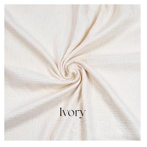 May include: Ivory-colored fabric with a textured, crinkled appearance, arranged in a swirling pattern. The word "Ivory" is printed in a black, sans-serif font at the bottom. The fabric appears soft and lightweight.