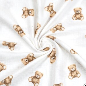 May include: White fabric with a repeating pattern of brown teddy bears. The bears are in various poses, some sitting and others lying down. The fabric has a soft, textured appearance.