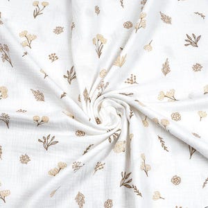 May include: White fabric with a repeating pattern of tan and brown floral and leaf designs. The fabric is soft and appears to be muslin or a similar lightweight material. The floral elements include various flower and leaf shapes.
