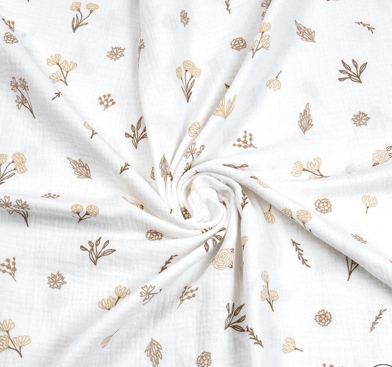 May include: White fabric with a repeating pattern of tan and brown floral and leaf designs. The fabric is soft and appears to be muslin or a similar lightweight material. The floral elements include various flower and leaf shapes.