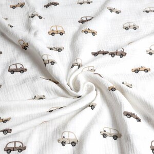 May include: White fabric with a repeating pattern of small, vintage-style cars in shades of brown and tan. The cars are evenly spaced across the soft, textured material, creating a playful and whimsical design.