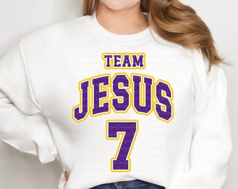 May include: White sweatshirt with purple and yellow text that reads "Team Jesus 7".