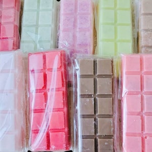 May include: Assortment of ten wax melts in various colors and scents, including pink, red, brown, white, and green. Each melt is individually wrapped in clear plastic.