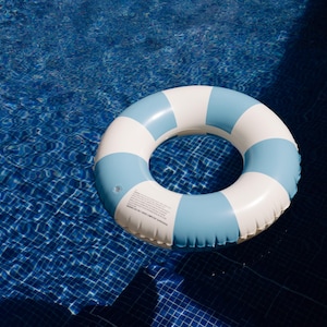 May include: A white and blue inflatable ring float for swimming in a pool.