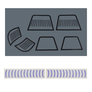 May include: A collection of black, geometric shapes, including trapezoids and curved forms with parallel lines, are arranged on a gray background. Two strips of white tape with blue vertical stripes are at the bottom.