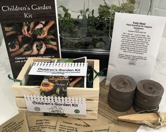 May include: A wooden crate filled with seed packets for a children's garden kit. The packets are labeled with the names of different vegetables, including carrots, tomatoes, snap peas, and mini pumpkins. The kit also includes a small clear plastic dome, a wooden trowel, and a bag of kelp meal.