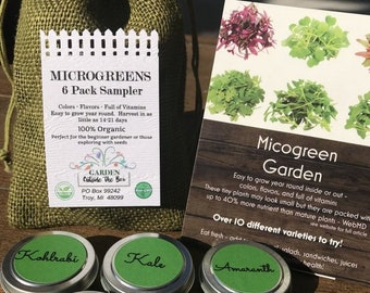 May include: A set of six small green and silver tins containing microgreen seeds. The tins are labeled with the names of the microgreens: Kohlrabi, Kale, Amaranth, Beet, Alfalfa, and Radish. The tins are arranged in a circle on a wooden surface. The image also includes a small burlap bag with a label that reads "Microgreens 6 Pack Sampler".