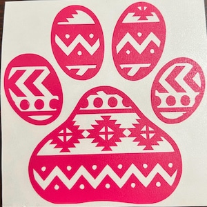 Puede incluir: Una pegatina de huella de pata rosa intenso con un patrón decorativo. La huella de la pata se compone de cinco almohadillas, cada una con un diseño único. Los diseños incluyen zigzags, chevrones y formas geométricas.