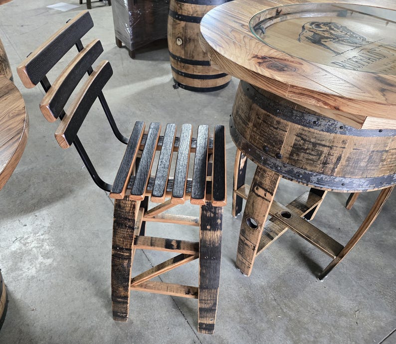 May include: A set of rustic bar furniture made from reclaimed wood. The set includes a bar stool with a slatted seat and back, and a round bar table. The wood has a natural finish with dark accents.