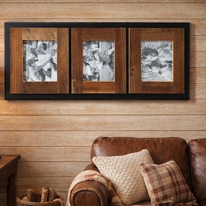 May include: A rustic wooden picture frame with three openings, each displaying a black and white photograph. The frame has a dark border and is mounted on a wooden wall. The room features a leather sofa and a fireplace.