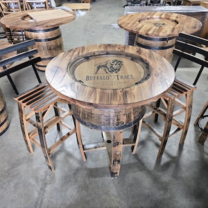 May include: Rustic wooden bar tables and stools made from repurposed barrels. The round tables feature a wooden tabletop with a recessed center, and the "Buffalo Trace" logo is visible. The stools have a slatted seat design.