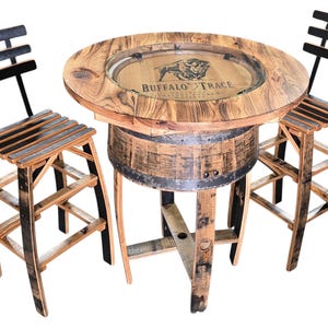 May include: A rustic bar table and two matching chairs made from reclaimed wood. The round table features a glass top with the "Buffalo Trace" logo. The chairs have slatted seats and backs. The set is made from repurposed barrels.