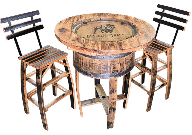 May include: A rustic bar table and two matching chairs made from reclaimed wood. The round table features a glass top with the "Buffalo Trace" logo. The chairs have slatted seats and backs. The set is made from repurposed barrels.