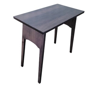 May include: A dark wood folding table with a simple design. The table has a rectangular top and four legs.