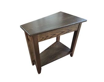 May include: A dark brown wooden end table with a triangular top and a lower shelf. The table has a simple, traditional design.