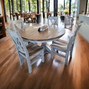 May include: A rustic dining set featuring a round wooden table and four matching chairs. The table and chairs have a distressed white finish, with natural wood tones visible. The chairs have a unique X-back design.