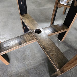 May include: Close-up of a wooden chair with a rustic design. The chair features a dark stained frame with a natural wood seat and back. The chair is made from reclaimed wood and has a unique, handcrafted appearance.