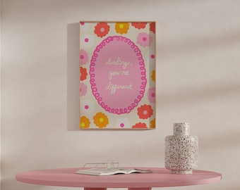 May include: A pink round table with a white book on top, surrounded by three pink and brown stools. A framed print with pink flowers and the text "darling, you're different" hangs on the wall behind the table.