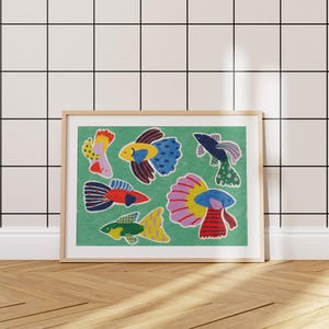 May include: A framed art print featuring colorful, stylized fish illustrations on a green background. The fish have various patterns and colors, including yellow, blue, red, and pink. The frame is a light wood color, and the artwork is displayed against a white tiled wall.