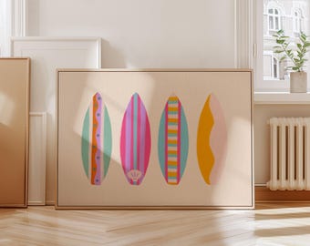 May include: A framed artwork featuring four colorful surfboards. The surfboards are painted in shades of green, pink, blue, and yellow, with various stripe and design patterns. The artwork is displayed on a light beige background.