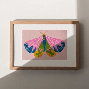 May include: A framed print of a colorful butterfly with pink, green, blue, and yellow wings against a light pink background.