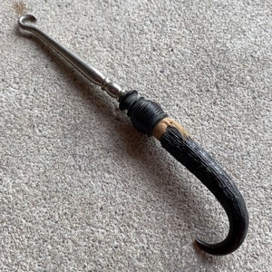 Peut inclure: Un chausse-pied en argent avec une poignée en corne noire et brune.