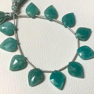 May include: A strand of faceted, teardrop-shaped Amazonite gemstone beads in varying shades of teal and green. The beads are strung on a silver wire, with a matching teal tassel at the top. These beads are ideal for jewelry making.