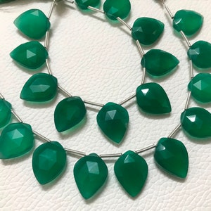 May include: A strand of green gemstone beads, each bead is faceted and shaped like a teardrop. The beads are strung on a silver wire.