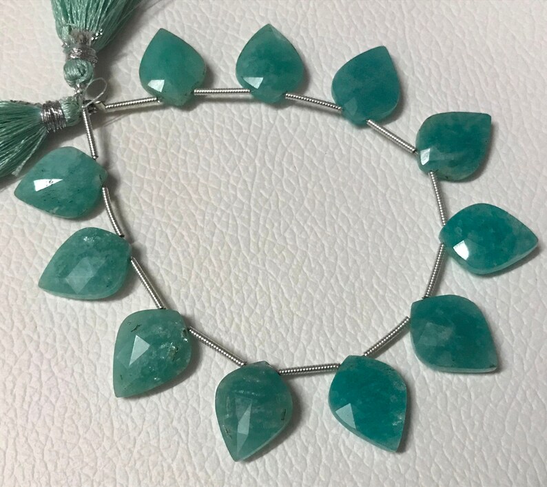 May include: Strand of faceted, teardrop-shaped Amazonite beads in shades of teal and turquoise. The beads are strung on a silver-colored wire, with a matching teal tassel at the top. These beads are ideal for jewelry making.