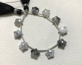 May include: A strand of white and black star-shaped gemstone beads strung on a silver wire. The beads are faceted and have a natural, organic look.