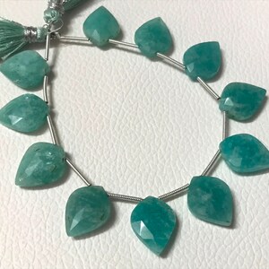 May include: Strand of aqua-colored gemstone beads, each shaped like a leaf with faceted surfaces. The beads are strung on a silver-colored wire, with a tassel at the top. The beads are approximately 1 inch in length, suitable for jewelry making.