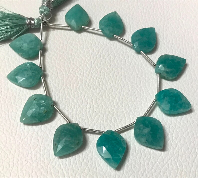 May include: Strand of aqua-colored gemstone beads, each shaped like a leaf with faceted surfaces. The beads are strung on a silver-colored wire, with a tassel at the top. The beads are approximately 1 inch in length, suitable for jewelry making.