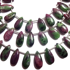 Może przedstawiać: Szereg zielonych i różowych koralików z kamieni szlachetnych, każdy koralik ma kształt łzy. Koraliki są nawleczone na srebrny drut.