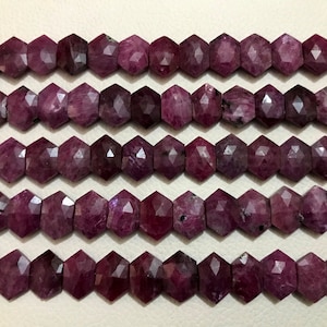 May include: A strand of faceted ruby beads, each bead is a deep reddish-purple color and has a hexagonal shape.