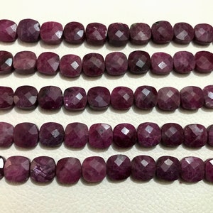 May include: A strand of deep purple gemstone beads, each bead is faceted and has a square shape.