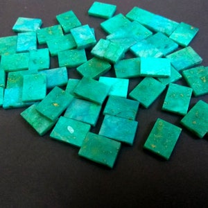 May include: A pile of turquoise green rectangular tiles with gold flecks. The tiles are arranged in a random pattern and are all the same size.