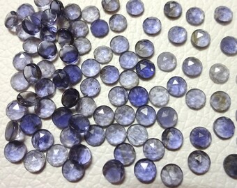 May include: A collection of 50 loose, faceted, round, purple-blue gemstones. The stones are approximately 6mm in diameter and have a variety of shades of purple and blue.