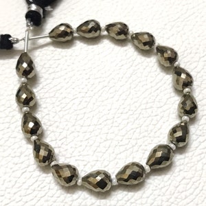 May include: A strand of faceted pyrite beads in a teardrop shape. The beads are a dark, metallic gold colour and are strung on a silver wire.