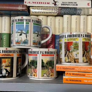 May include: Four white ceramic mugs with illustrations and the text "P.G. Wodehouse" are displayed in front of a bookshelf filled with books. The mugs feature different scenes and book titles. The mugs are on a gray shelf.