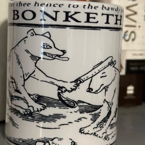 May include: White ceramic mug with a black and white illustration of two dogs. The mug has the text "Get thee hence to the bawdy court" and "BONKETH" printed on it.